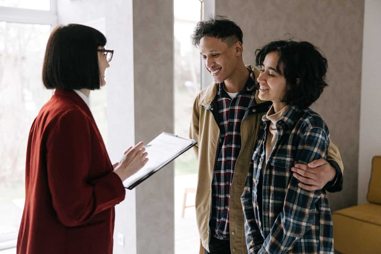 Woman talking to the couple while holding a clipboard 8962682